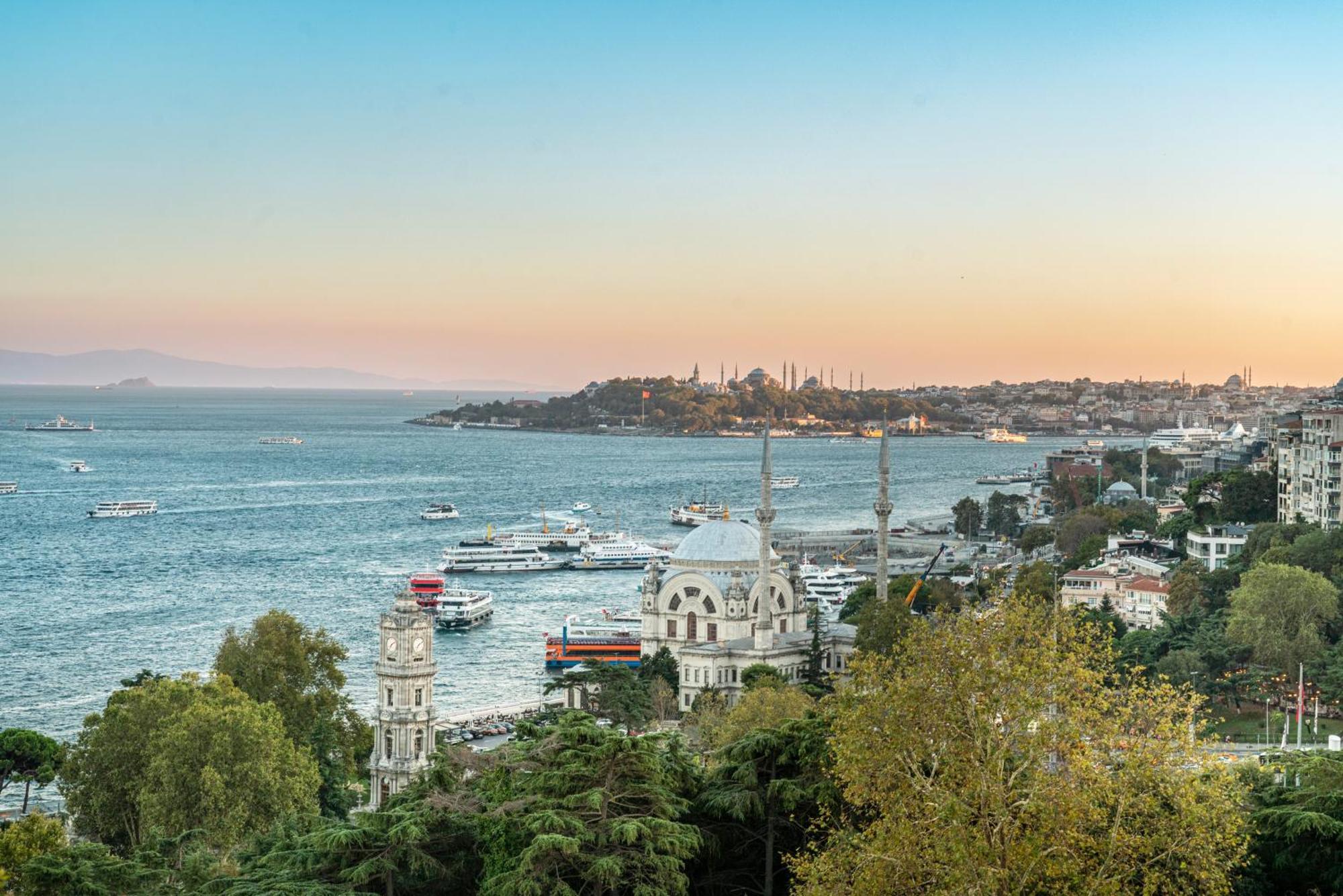 Swissotel The Bosphorus Istanbul Luaran gambar The photo shows a picturesque view of a coastal area during the evening, with a serene body of water. In the foreground, there are several trees and buildings, including distinctive architectural structures, likely mosques or historical sites, with m
