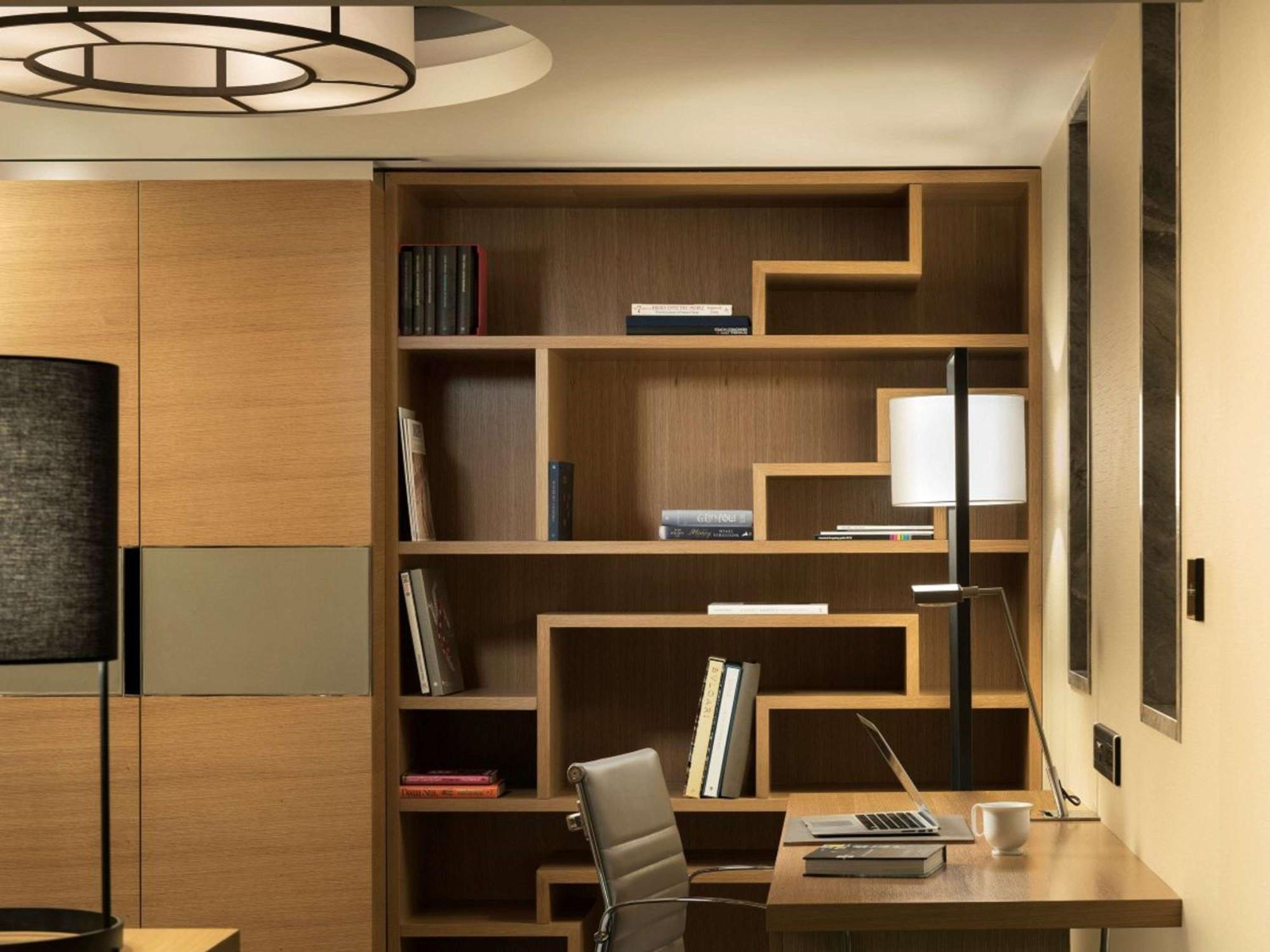 Swissotel The Bosphorus Istanbul Luaran gambar The photo depicts a modern office or study space featuring a stylish wooden bookshelf designed with a geometric pattern. The bookshelf contains several books and decorative items. To the right, there's a sleek desk with a laptop, a chair, and a desk 