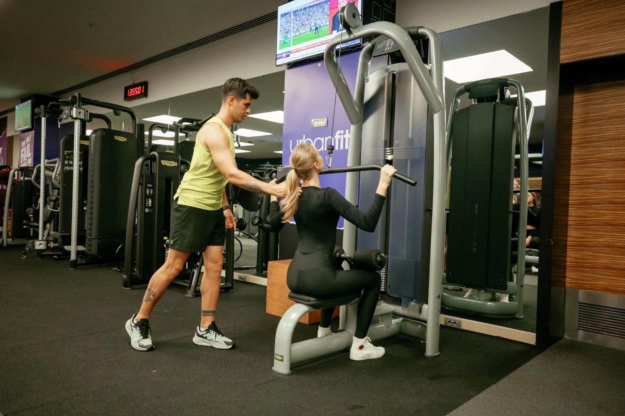 Swissotel The Bosphorus Istanbul Luaran gambar The photo shows a gym scene where a man is assisting a woman with her workout. The woman is seated on a weight machine, performing a rowing exercise, while the man stands beside her, likely providing support or guidance. In the background, there is a